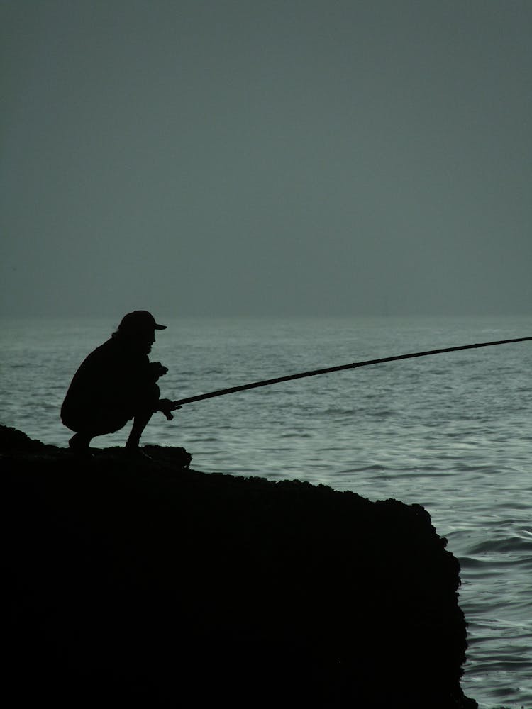 Silhouette Of A Person Fishing On The Ocean