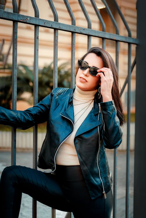 A Woman in Black Leather Jacket and Black Sunglasses Posing