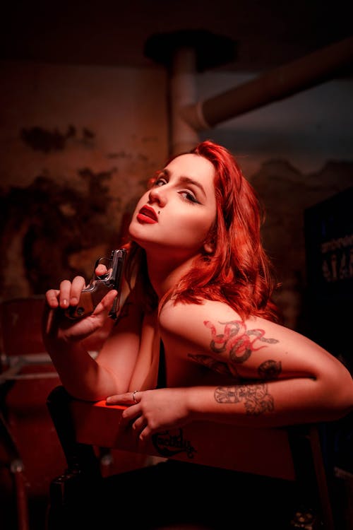 Woman with Tattoos Posing with Pistol