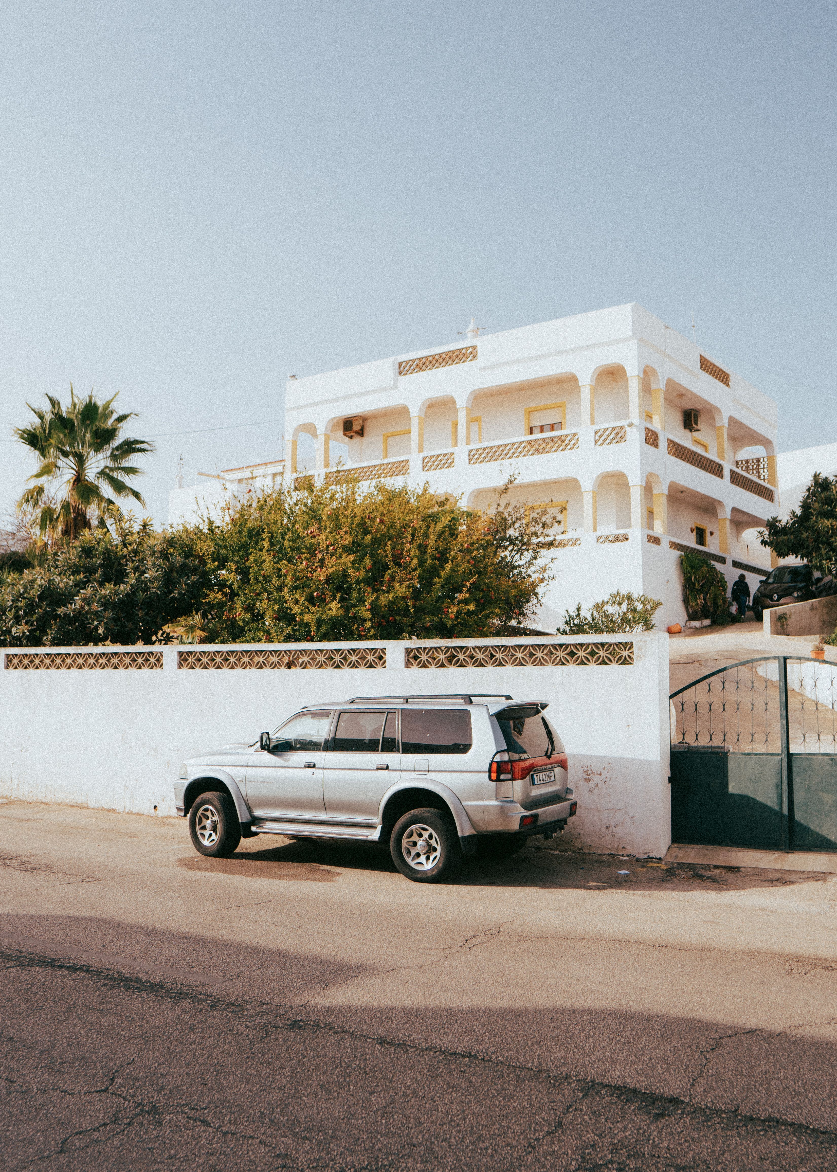 A silver SUV parked on a sunny street with a white building backdrop in Albufeira, Portugal.