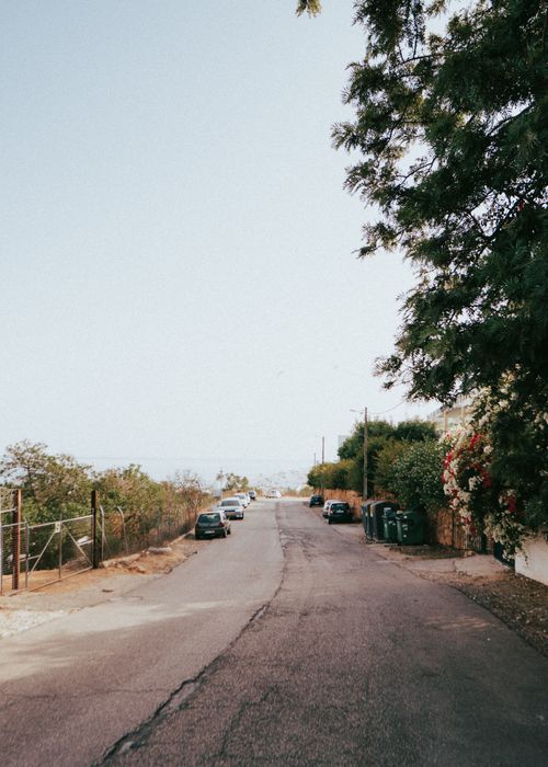Free A serene suburban road in Albufeira, Portugal, lined with cars and trees under clear skies. Stock Photo