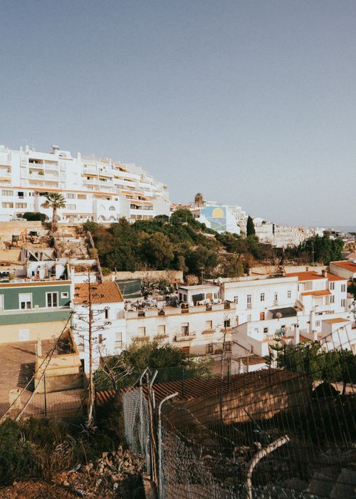 Free Charming hillside urban landscape of Albufeira with white buildings and lush greenery. Stock Photo