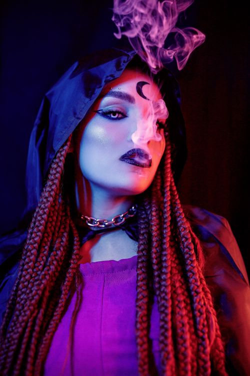 Free Close-up of a mystical woman with braided hair and smoke in a dramatic setting. Stock Photo