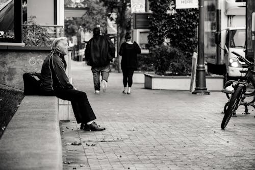 Free Grayscale Photography of Man Sitting on Bench Stock Photo