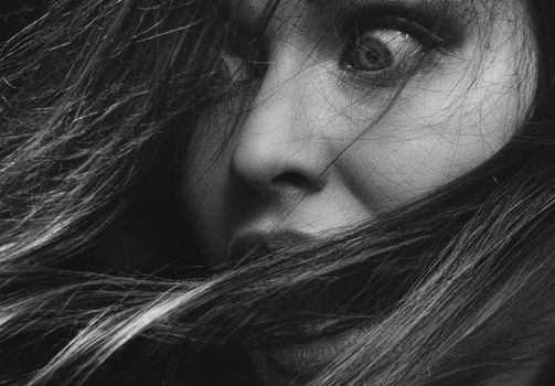 Intense monochrome close-up of a woman's expressive face and hair.