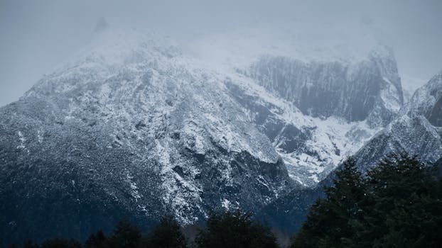 Captivating view of snow-covered mountains under cloudy skies, evoking a serene winter atmosphere.