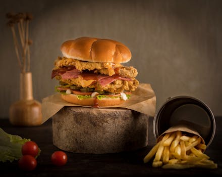 Close-up of a juicy gourmet hamburger with crispy fries on a rustic wooden surface.