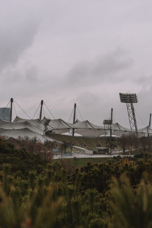 Free A contemporary stadium with unique architecture under an overcast sky, surrounded by greenery. Stock Photo
