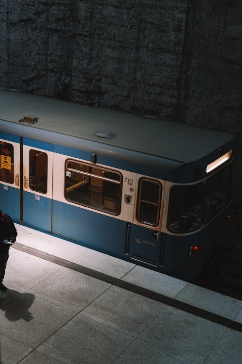Blue and White Subway Train Near Concrete Wall