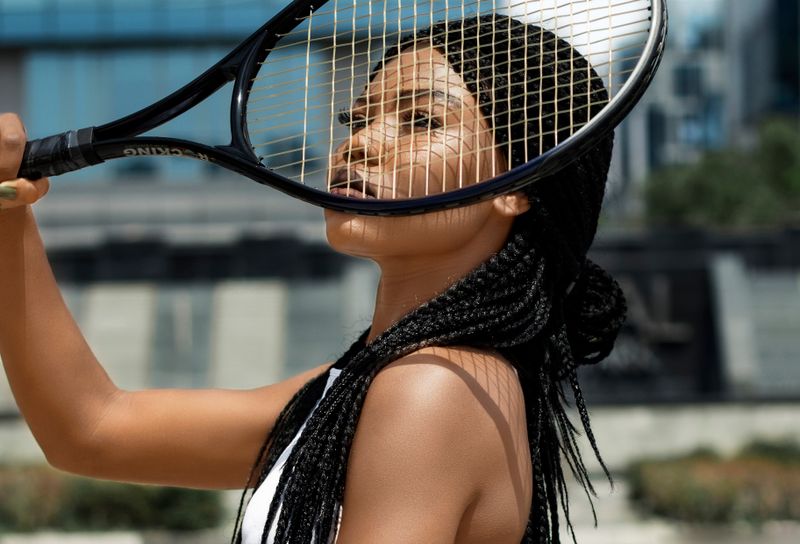 Woman with long braids holding tennis racket
