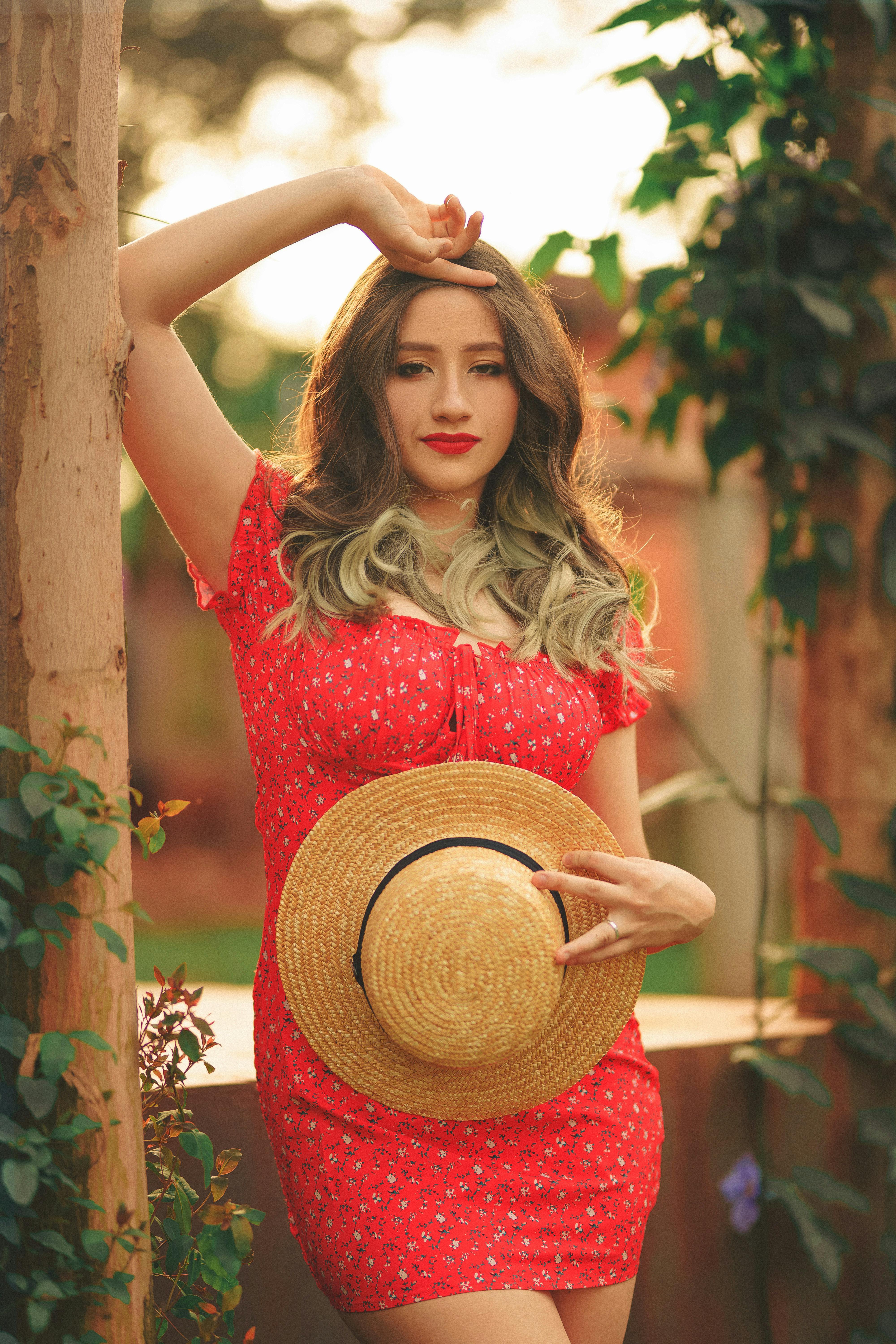Woman in Red Dress Holding a Large Sun Hat · Free Stock Photo