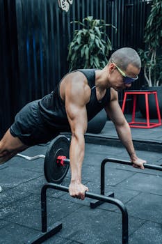 Adult man doing push-ups using barbells in a Mexico City gym, showcasing fitness and strength.