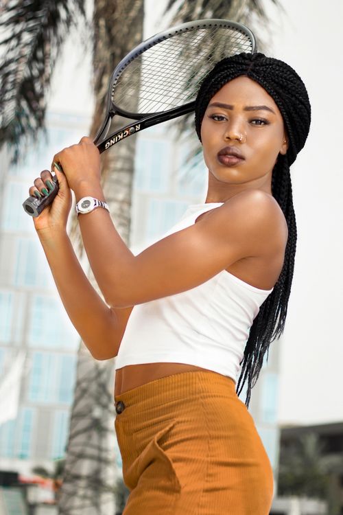 Free Trendy young African woman posing with a tennis racket in an urban setting. Stock Photo