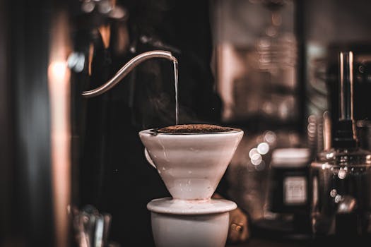 Artistic shot of hot water pouring into a dripper for perfect pour over coffee in a café.