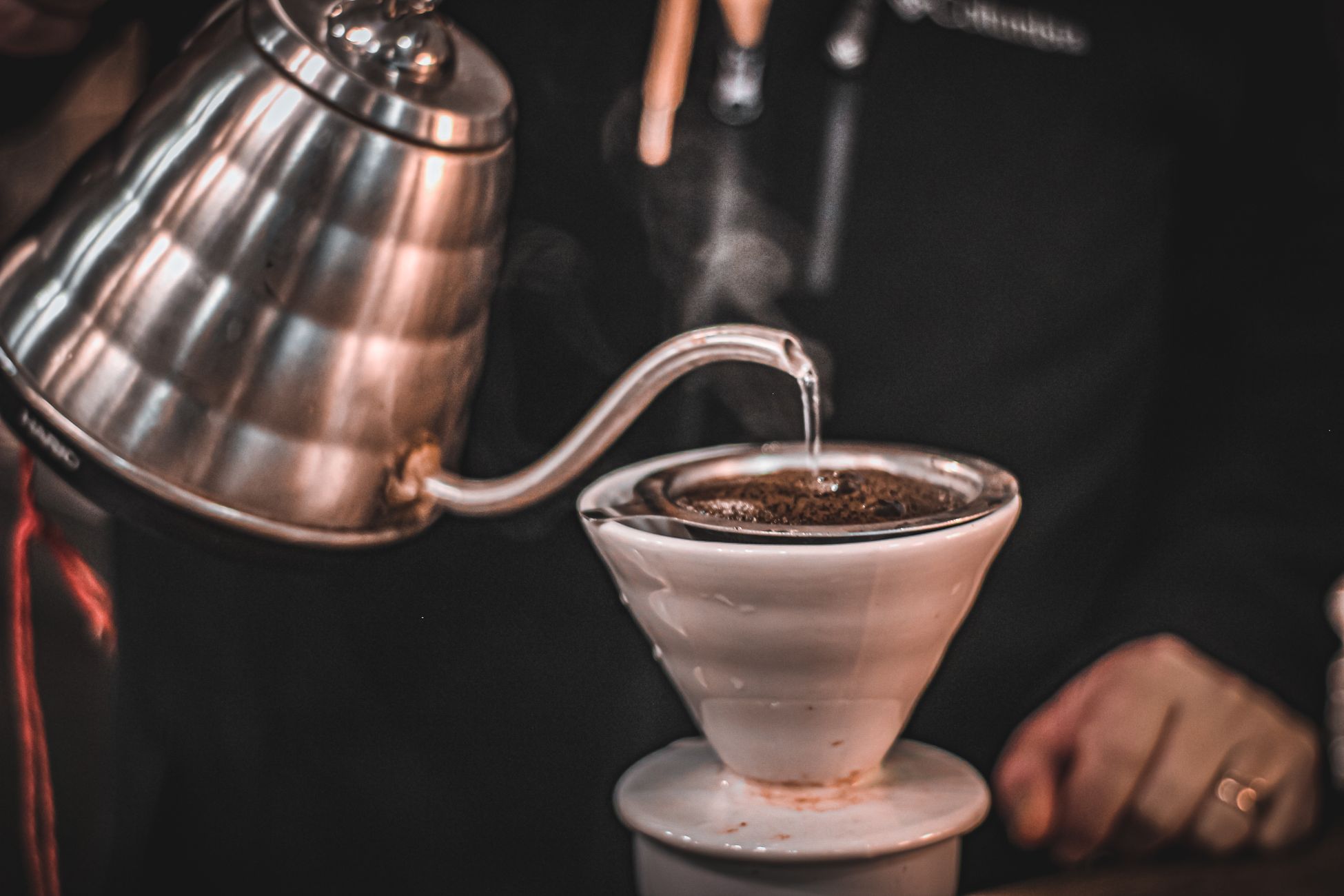 Steam rises as hot water is poured over coffee grounds in a pour-over coffee maker.