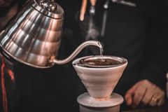 Steam rises as hot water is poured over coffee grounds in a pour-over coffee maker.