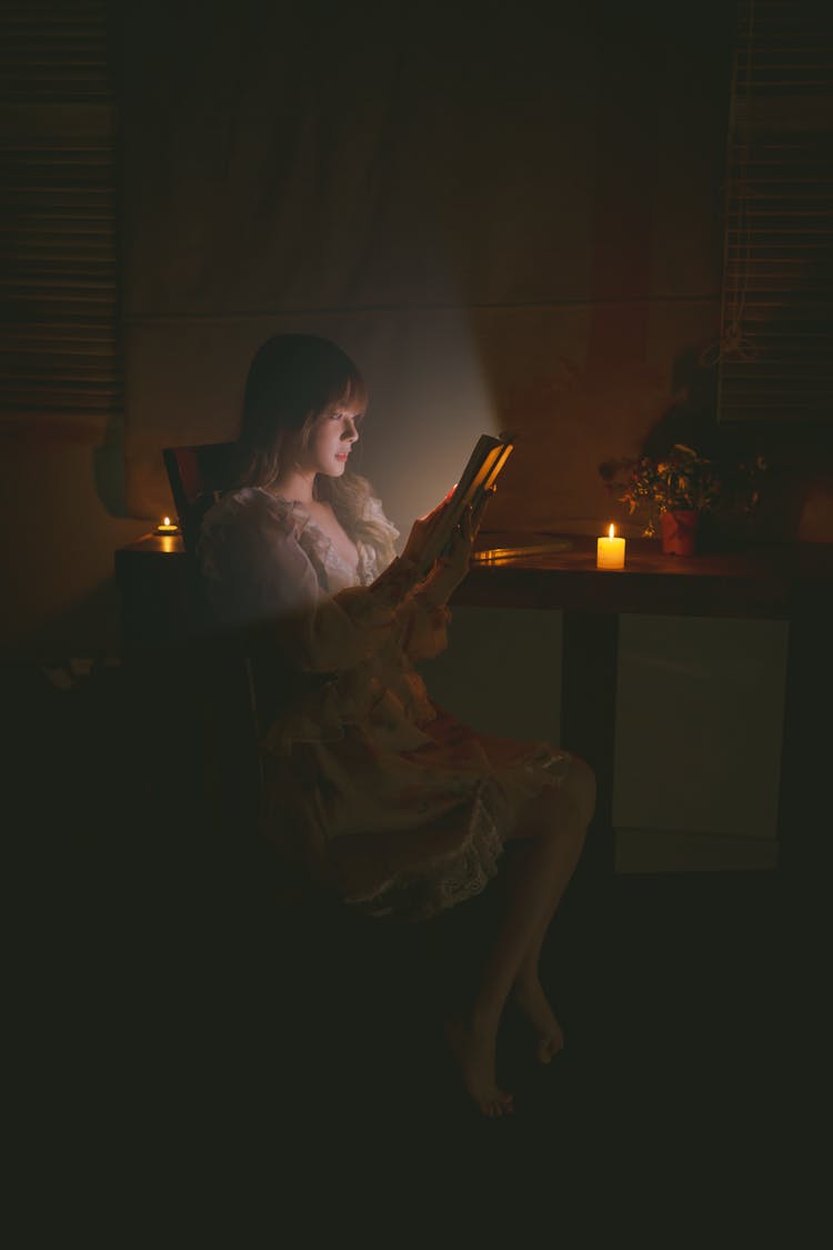 Woman Reading In The Dark Illuminated By The Book Light 