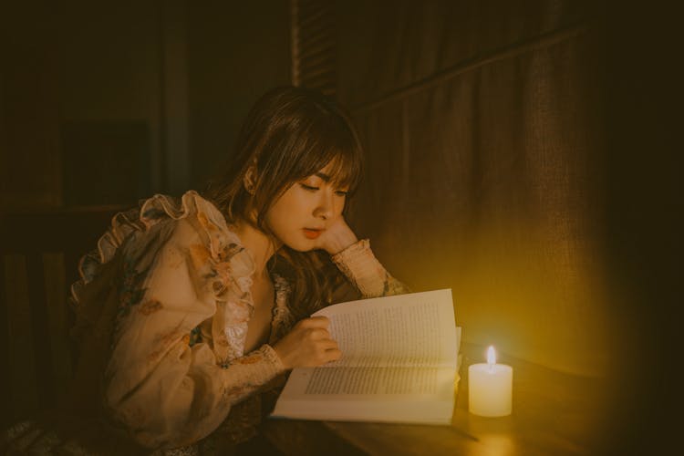 Woman Reading Book With Wax Candle