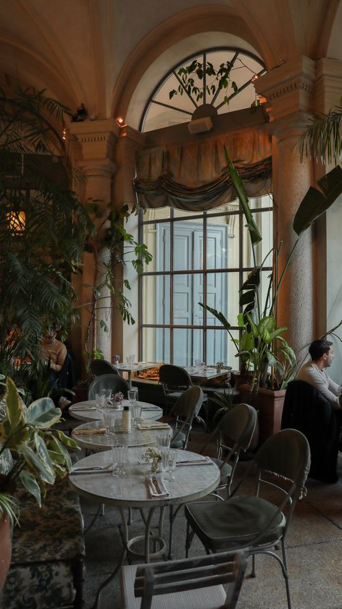 Free Luxurious Milanese cafe with lush plants and stylish decor in an urban setting. Stock Photo
