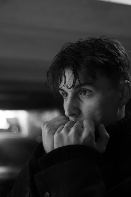 Free Expressive black and white portrait of a young man with thoughtful gaze and covered fists. Stock Photo