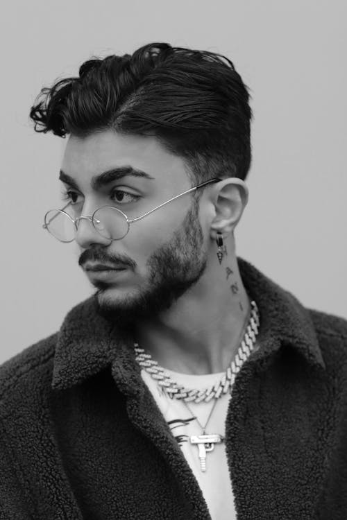 A Grayscale Photo of a Man in Fleece Jacket Wearing Eyeglasses