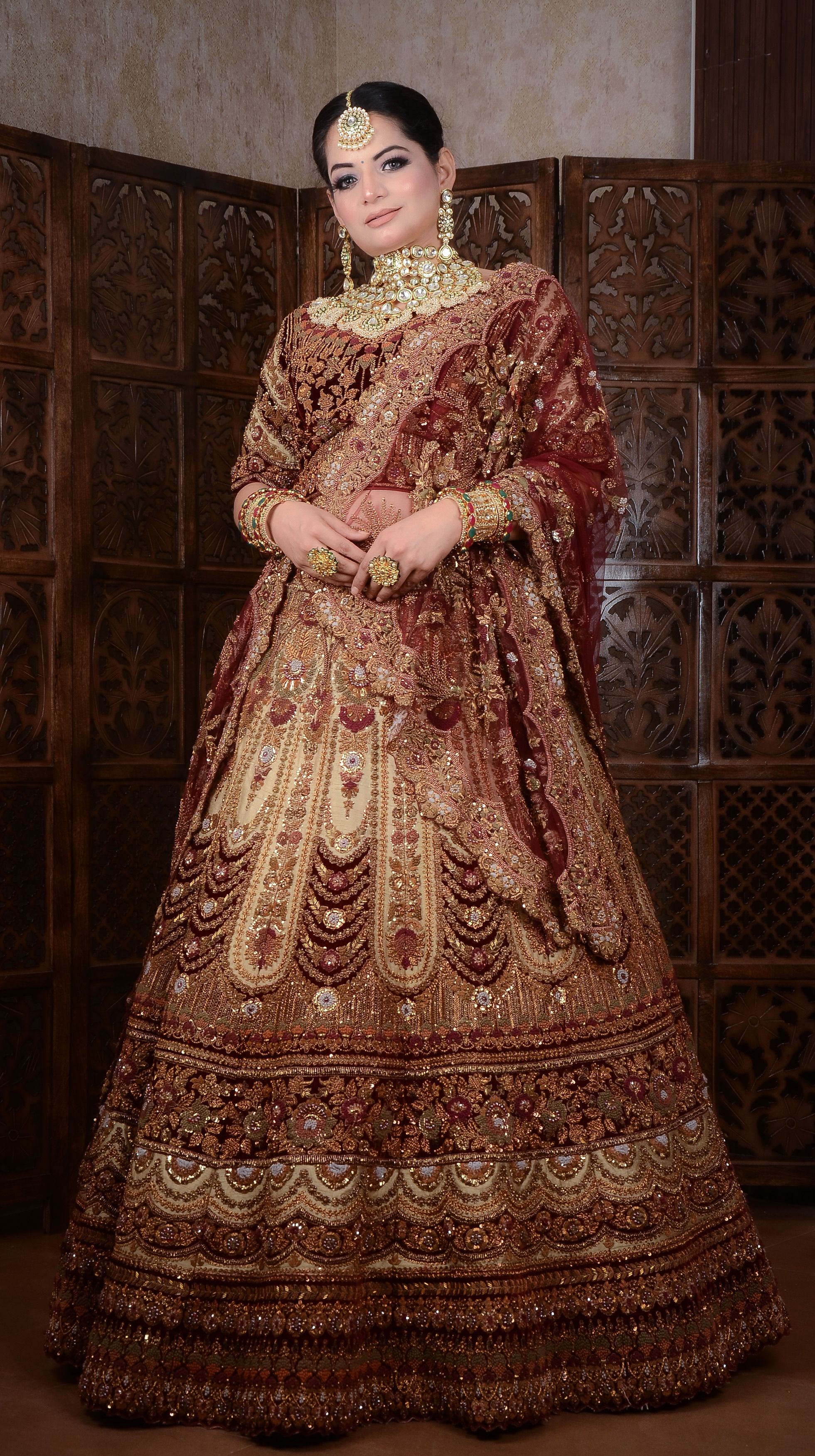 Portrait of a woman in traditional Indian bridal attire with ornate jewelry and intricate patterns.