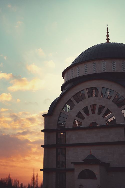 Free Dome of a mosque silhouetted against a vibrant sunset sky, showcasing intricate architecture. Stock Photo