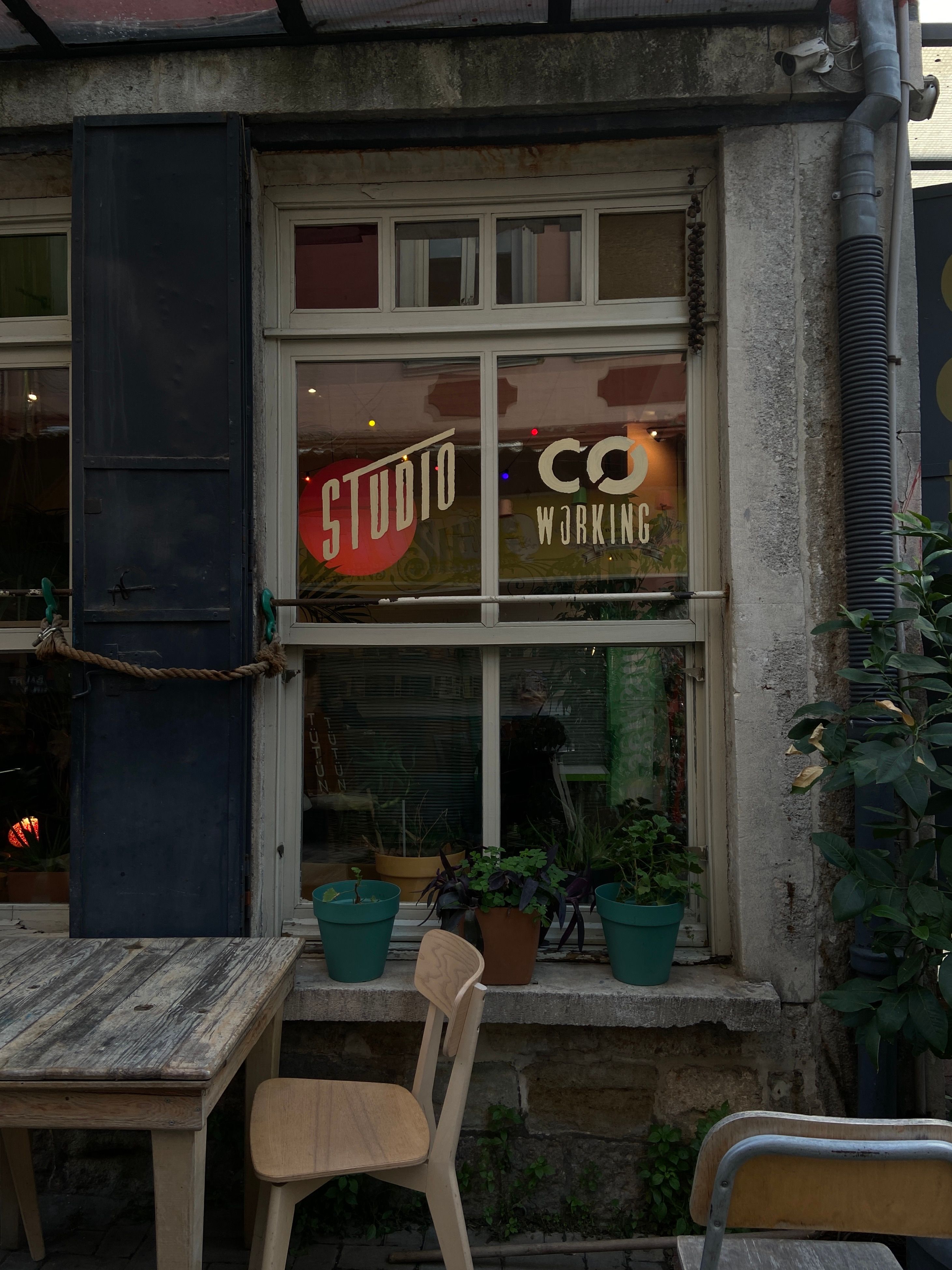 A cozy urban café exterior with vintage decor, showcasing a co-working space sign on the window.