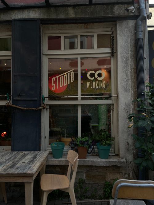Free A cozy urban café exterior with vintage decor, showcasing a co-working space sign on the window. Stock Photo
