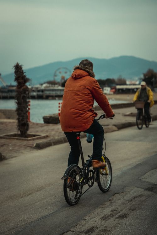 Free A man rides a bicycle on a coastal path dressed warmly for autumn weather. Stock Photo