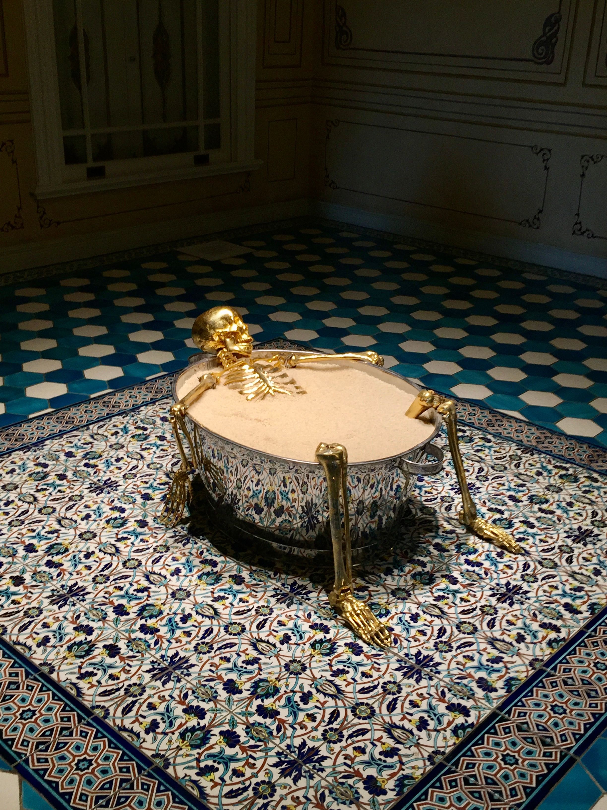 A modern art installation featuring a golden skeleton in a decorative bathtub in Istanbul.