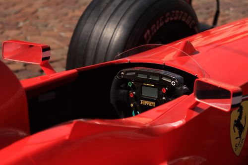 Free Dynamic close-up view of a red formula one racing car cockpit, showcasing the steering wheel and controls. Stock Photo