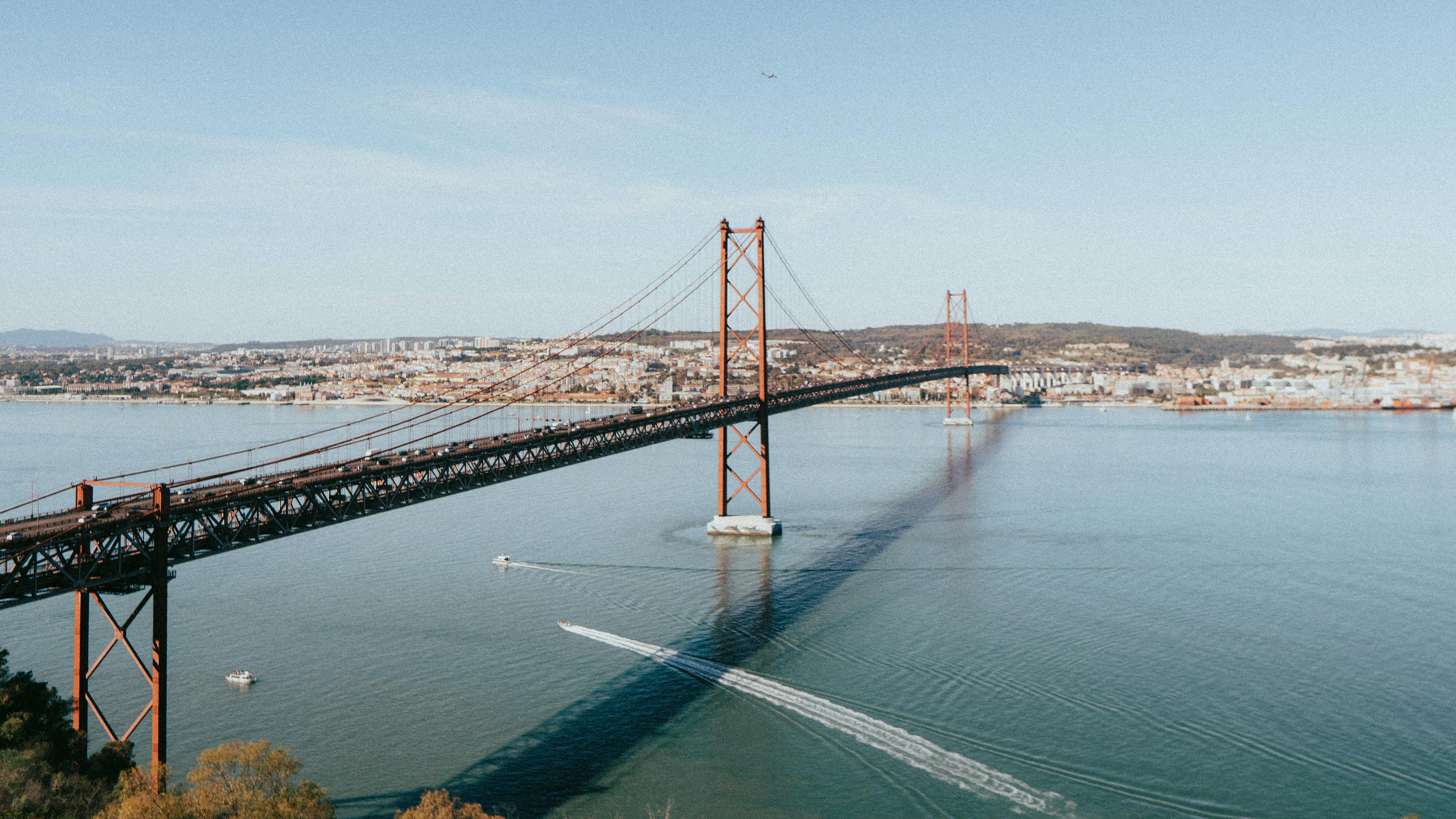 A stunning view of the 25 de Abril Bridge spanning the Tagus River in Lisbon, Portugal, on a sunny day.