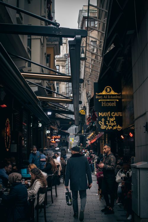 Free A bustling narrow street in Istanbul lined with cafes, filled with people walking and dining outdoors. Stock Photo