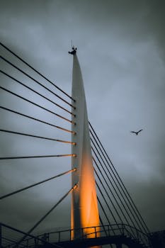 Suspension bridge with moody sky and warm lighting, captured in low angle view.