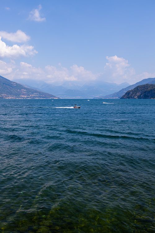 Free Peaceful summer day at Lake Como, Bellagio with motorboat and mountains. Stock Photo