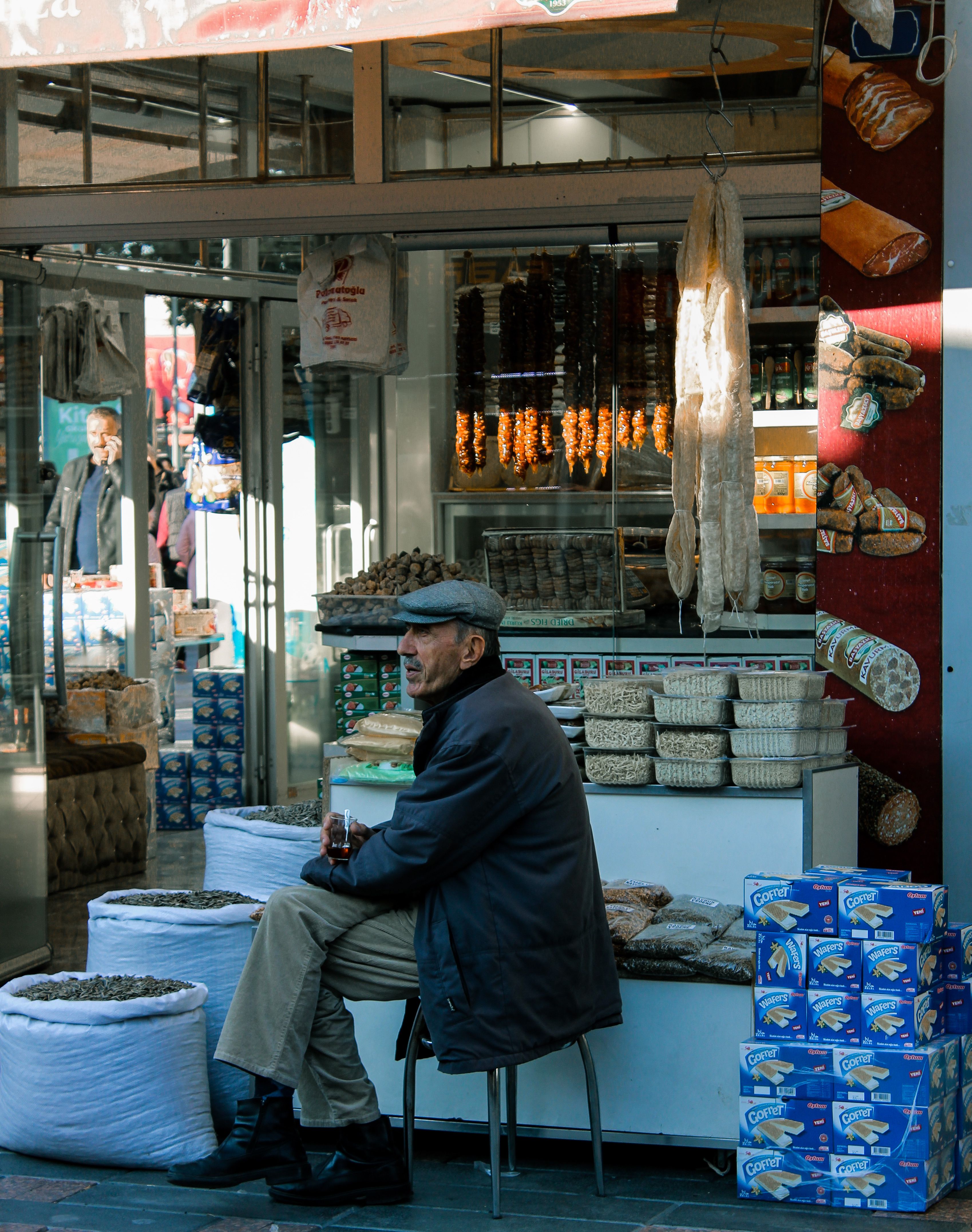 Man Sitting near Store · Free Stock Photo