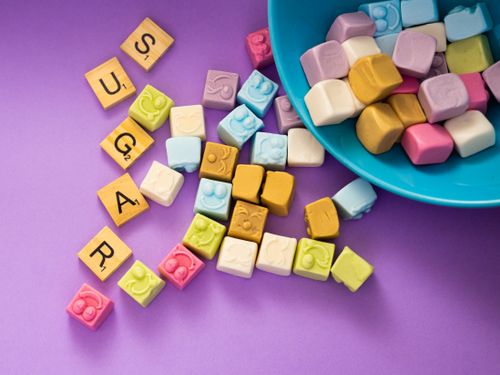 Free Vibrant colorful candy cubes with scrabble letters spelling 'SUGAR' on a purple background. Stock Photo