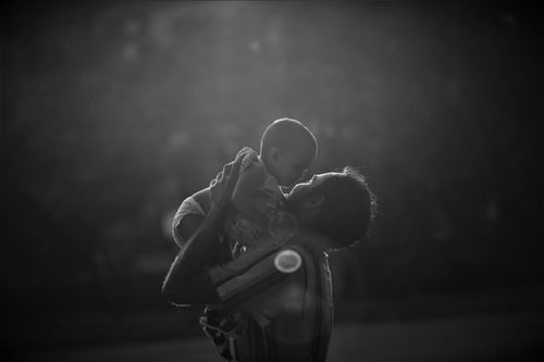 Free Silhouetted father lifting baby in a touching grayscale moment. Stock Photo