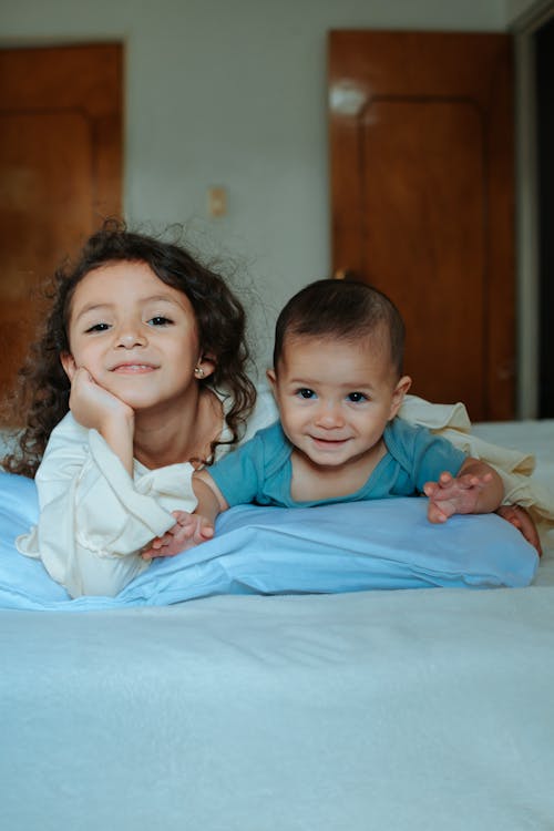 Free Girl and Baby Boy Posing on the Bed Stock Photo