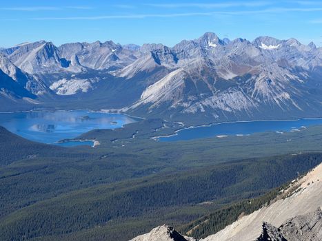 A breathtaking view of mountain ranges with shimmering lakes and clear blue skies.