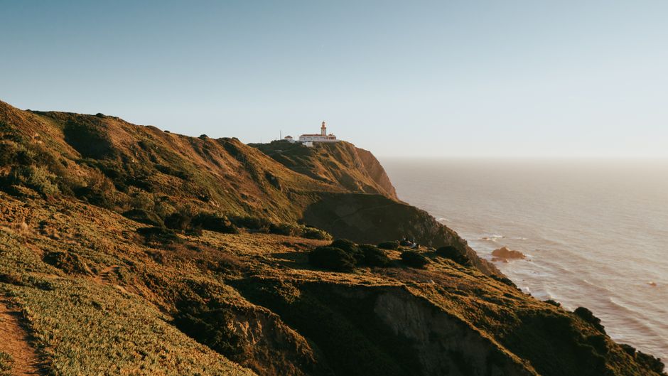 View of Cabo da Roca lighthouse perched on a rugged cliff overlooking the ocean in Portugal.
