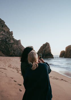 A scenic view of Praia da Ursa, featuring rocky cliffs and a sunset beach scene.