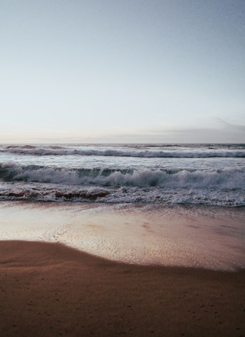 Free Calm ocean waves crashing at dawn on a sandy beach, creating a tranquil atmosphere. Stock Photo