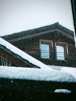 Charming wooden house exterior covered in snow, capturing serene winter atmosphere with snowfall.