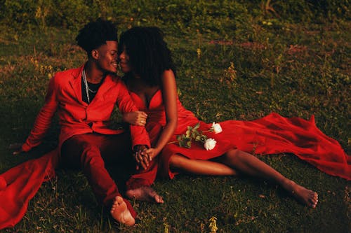 Couple in Red Outfits Sitting on the Ground 