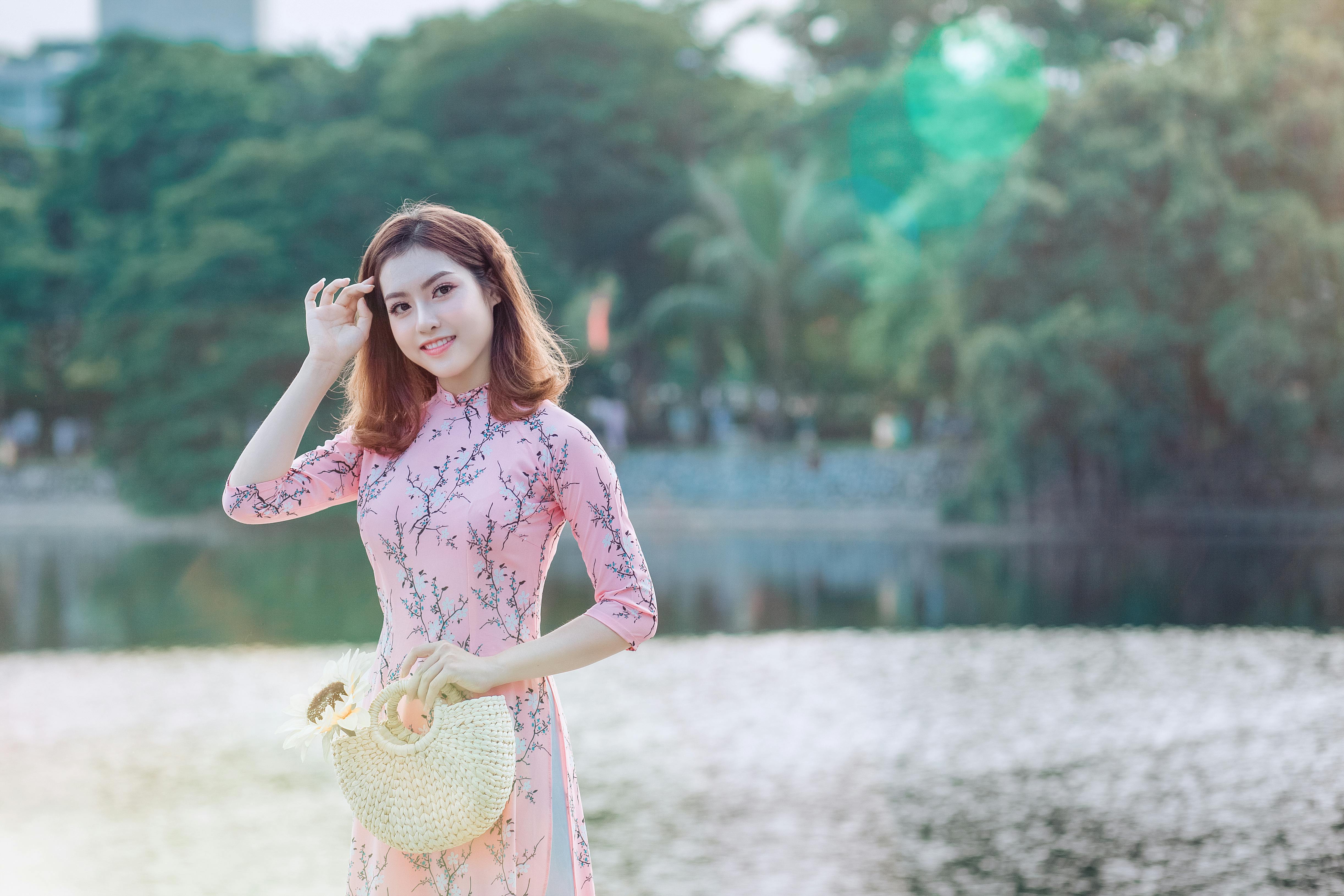 woman holding handbag near body of water