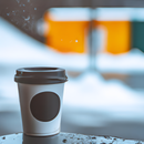 Close-up of a steaming disposable coffee cup with a winter backdrop and blurred urban elements.