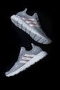 Top view of stylish known sports shoes with gray laces and breathable surface with pink strips and white soles for comfortable training on black surface