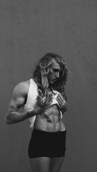 Powerful black and white portrait of a muscular woman with long hair showcasing strength and confidence.